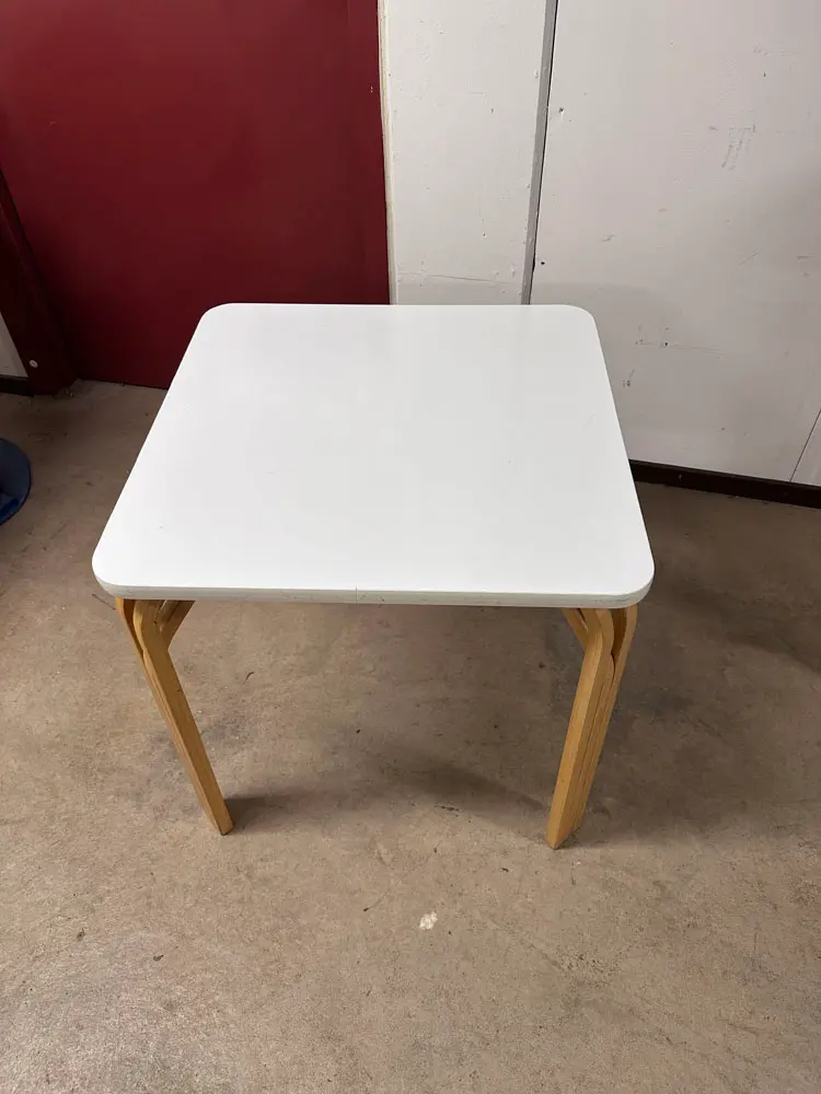 Litet bord med naturfärgade ben och vit bordsskiva