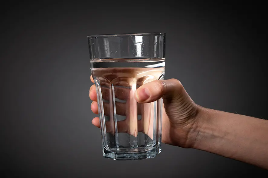 Hand som håller ett glas med vatten.